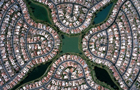 thumnail of plan view photo of a suburban area taken at altitude showing houses, roads and waterways symmetrically oriented in a four pointed diagonal cross like arrangement with the waterways forming the cross arms, intersecting in the middle at a pool